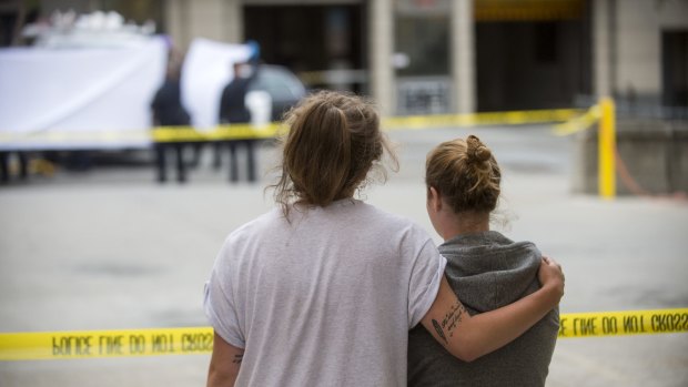 Two women embrace as police clear the scene.