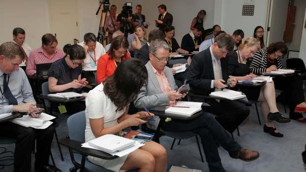 Journalists read their copies of the MYEFO ahead of the update from the government.