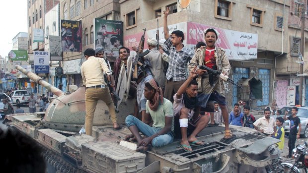 Militants loyal to Yemen's exiled government ride a tank they seized from Houthi militiamen in Taiz.