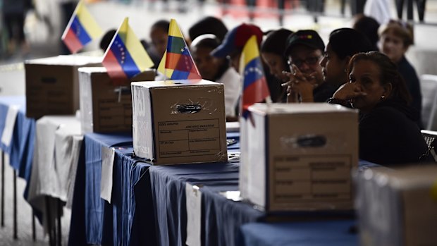 Polling officials wait for voters during the symbolic Venezuelan plebiscite in Caracas called by opposition parties.