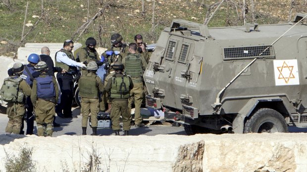 Israeli security forces stand at the scene of an alleged attack at Halhul checkpoint near Hebron, in the occupied West Bank,  after troops shot and killed a Palestinian man who allegedly attempted to ram his car into Israeli security forces.