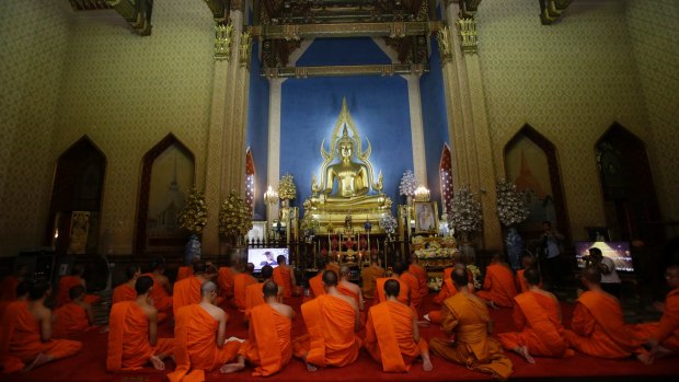 Thai Buddhist monks pray in front of a portrait of the new king.