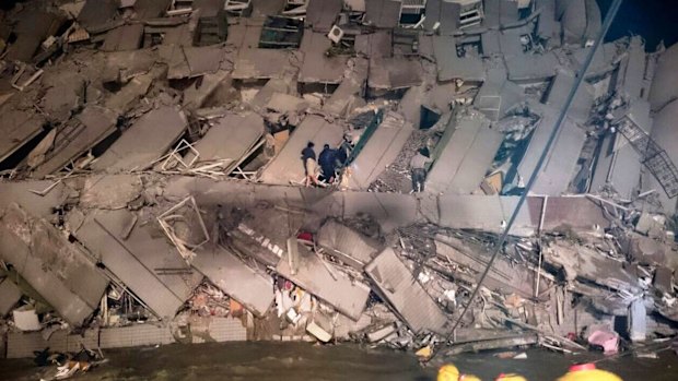 Rescuers try to enter an office building that collapsed on its side after the early morning earthquake in Tainan.