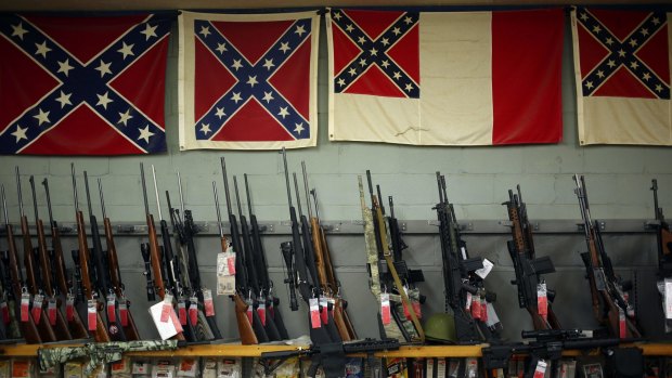 Confederate flags hang above various rifles for sale at the Knob Creek Machine Gun Shoot in Kentucky earlier this month. 
