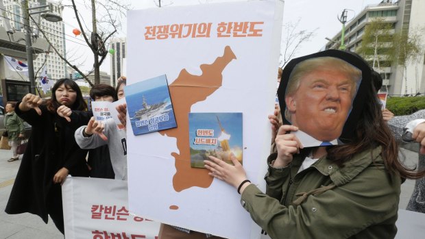 A South Korean protester holds a mask of US President Donald Trump and a Korean Peninsula map during a rally against US deployment in the region outside the US embassy in Seoul.