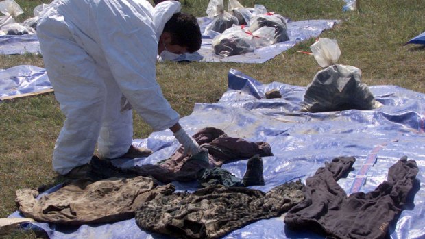 A forensic expert working for the UN  war crimes tribunal set out clothes, for families to identify, from human remains found in a central Kosovo mass grave in 1999.