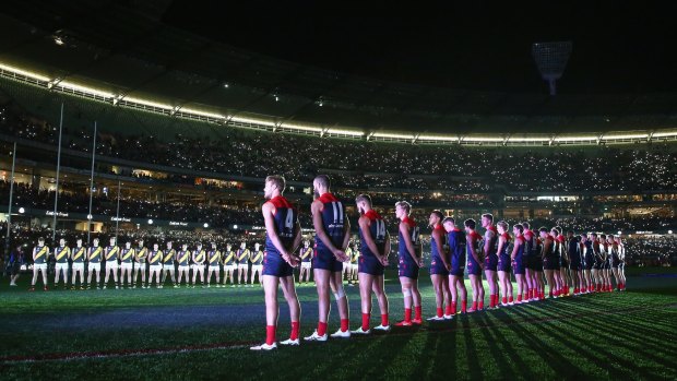 Melbourne and Richmond players line up for The Last Post at the MCG on Sunday night. 