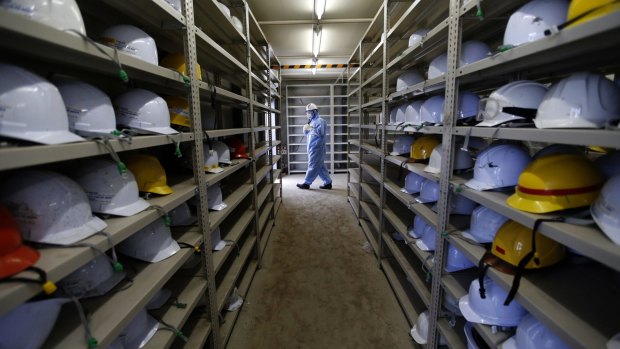 A worker leaves a room with shelves storing helmets at the tsunami-crippled Fukushima No.1 nuclear power plant on Wednesday.