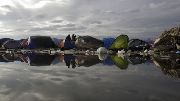 Tents are reflected in a puddle with waste inside the camp known as the Jungle in Calais, northern France.