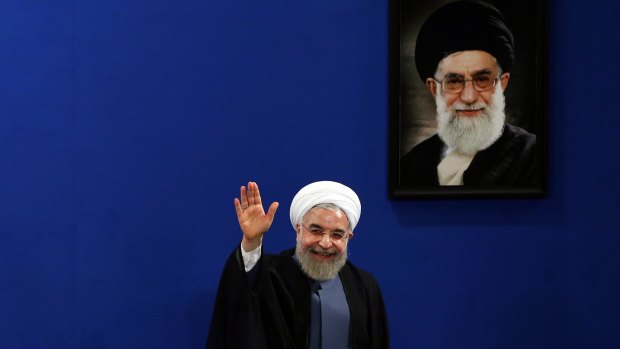 Iran's President Hassan Rouhani waves on the second anniversary of his election in June, in front of a portrait of Ayatollah Ali Khamenei.