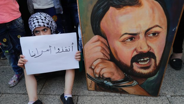 A Palestinian child holds a placard in support of "our prisoners" next to a painting of Marwan Barghouti in the Lebanese capital, Beirut.