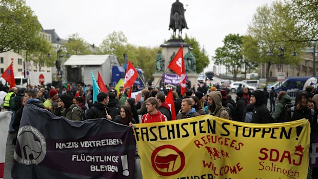  Two police officers were injured and a police car was set ablaze in Cologne as 15,000 people protested at the Alternative for Germany's party congress.