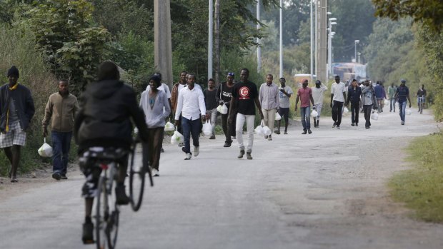 Migrants walk near the makeshift camp called "The New Jungle" in Calais, France, on Thursday.