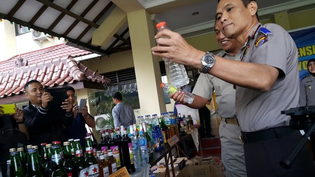 The Yogyakarta deputy police chief holding a bottle containing deadly bootleg alcohol at a press conference in Yogyakarta earlier this month. 