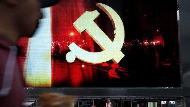 A man walks by digital display showing the Communist Party logo in Shanghai, China, on Saturday.