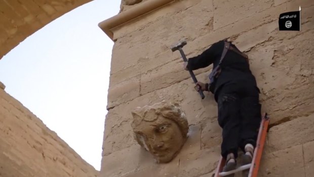 A militant hammers away at a face on a wall in Hatra, a large fortified city recognised as a UNESCO World Heritage site, south-west of Mosul, Iraq, in this image from a militant video released in April 2015.