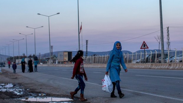 Refugees living in the Kilis refugee camp are seen walking along the road at the closed Turkish border gate on Tuesday. 