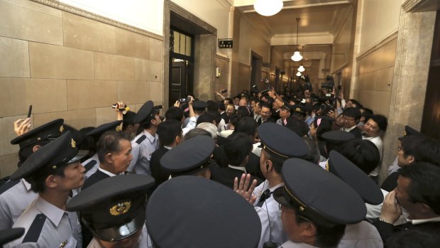Security guards surround opposition legislators who try to prevent others from entering the chamber of the committee on the security legislation in parliament's upper house in Tokyo on Wednesday.