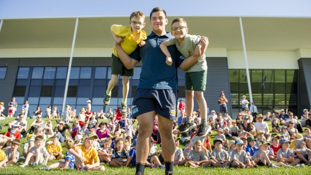 Brumbies giant Tyrel Lomax lifts up Lachlan, 7, and Nicolas, 8, at the Budding Brumbies school clinics.
