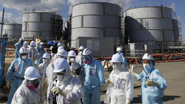 Members of a media tour group and plant workers wearing protective suits and masks at Fukushima nuclear power plant on Wednesday.