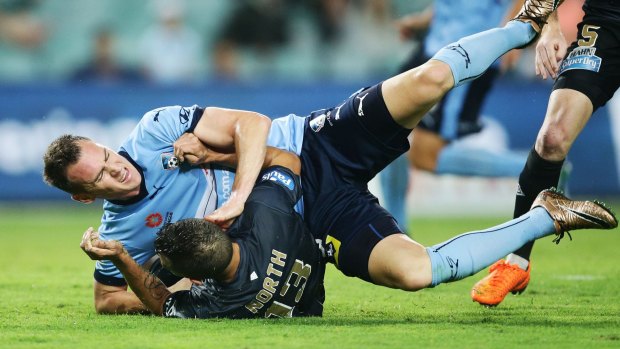 Down and out: Shane Smeltz of Sydney FC collides with Jade North of the Roar at Allianz Stadium.
