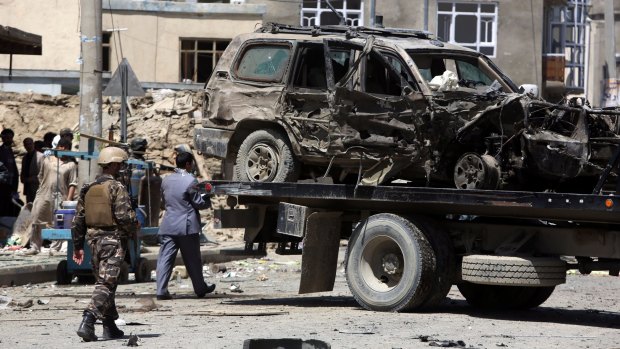 Afghan security forces remove a destroyed vehicle after a suicide bombing attack near Kabul's international airport on Sunday.