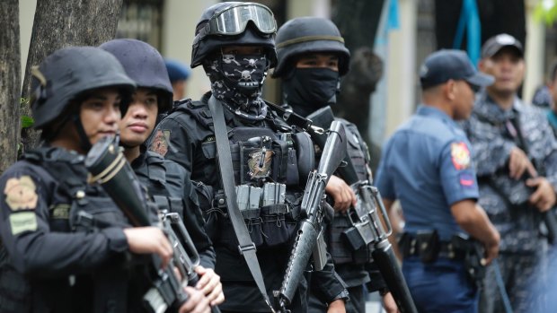 Armed police keep watch as men suspected of being Marawi militants arrive at the Department of Justice in Manila in July.