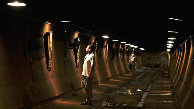 A tourist walks through underground tunnels constructed during World War II.
