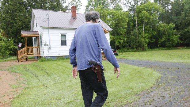 William Lobdell carries a handgun on his hip as he walks to a neighbour's house as the search for prison escapees David Sweat and Richard Matt continues.