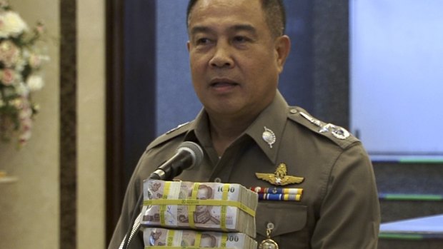 National police chief Somyot Poompanmoung holds a cash reward at a press conference in Bangkok on Monday. 