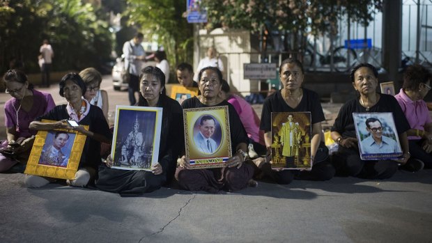 Women, dressed in black, hold portraits after the announcement of the death of Thailand's King Bhumibol Adulyadej.