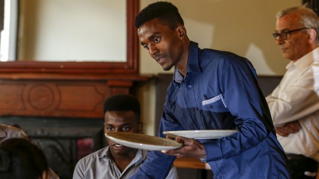 Melesse Asayhe (left) trains as a waiter with mentor Christos Vafeas (right) at the Empress Hotel.