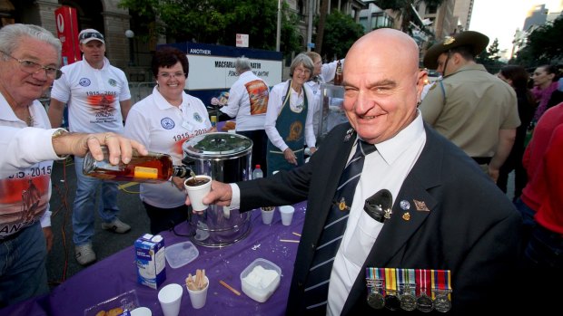 Darby Ashton, who served in Vietnam in 1965-1967, gets his coffee topped with rum by Lions volunteers Ross and Kim Forrest after more than 40,000 people gathered at the Shrine of Remembrance for the Brisbane Anzac Day dawn service.
