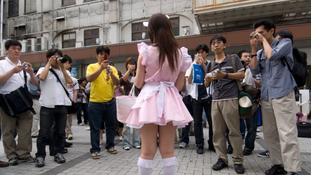 A maid advertises her cafe in Akihabara.