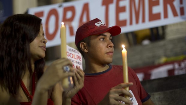 Demonstrators hold candles during a protest against Dilma Rousseff's impeachment in Rio de Janeiro on Tuesday where a sign reads "Out Temer". Pro-Rousseff rallies were held in cities in more than a dozen states. 