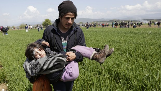 A migrant carries his daughter during a protest at the northern Greek border town of Idomeni, on Sunday.