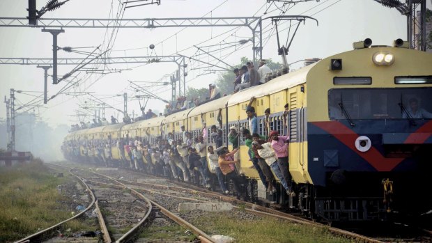 Indian passengers hang from the doors of the coaches of an overcrowded train in Bihar to travel home for the Chhath Puja festival earlier this month. 