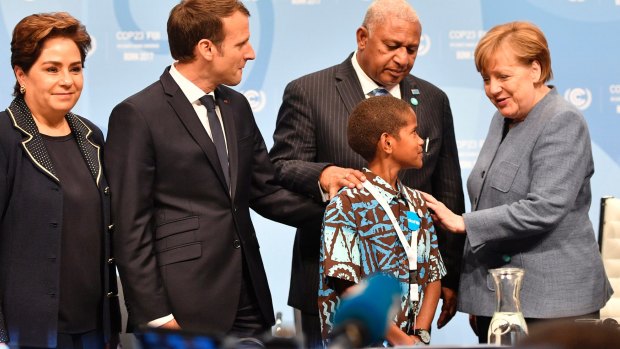 German Chancellor Angela Merkel, right, talks to Fiji prime minister and COP president Frank Bainimarama, second right, and Timoci Naulusala, a child from Fiji, with Patricia Espinosa, executive secretary of the United Nations Framework Convention on Climate Change, left, and French President Emmanuel Macron.