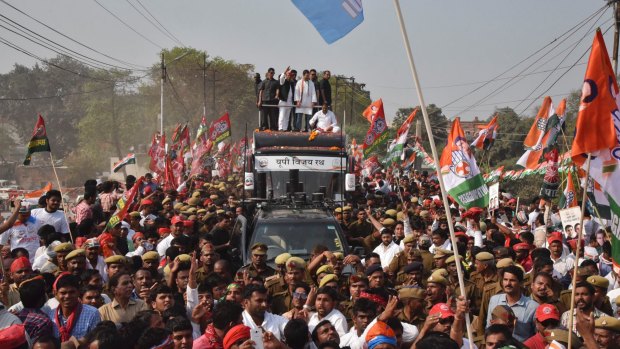 Uttar Pradesh state Chief Minister Akhilesh Yadav, red cap, and Congress party Vice President Rahul Gandhi, wearing tricolor shawl, cheer the crowd from atop a vehicle in Varanasi, India.