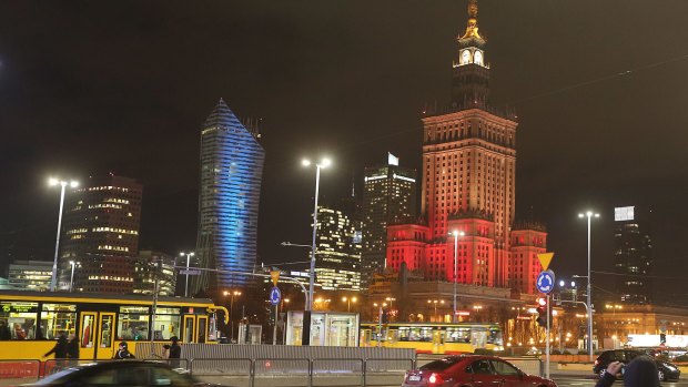 The Palace of Culture, right, the tallest building in the Polish capital, is lit in the colors of the Belgian flag in solidarity with the victims of the attacks in Brussels.