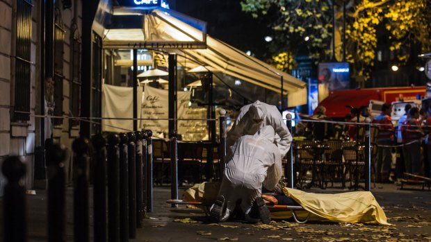 Investigating police officers inspect the body of a victim of the November 13 attacks outside the Bataclan concert hall in Paris, France.