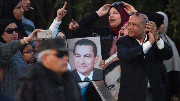 A small number of supporters of ousted former Egyptian President Hosni Mubarak hold posters with his photo, as they celebrate his acquittal, Cairo.