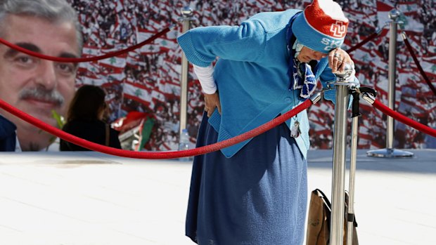 A woman mourns at the grave of former Lebanese prime minister Rafiq al-Hariri, pictured left, during the 10th anniversary of his assassination.