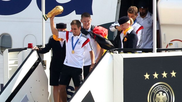 Home with the big prize: German captain Phillipp Lahm steps off the team plane in Berlin in Tuesday.