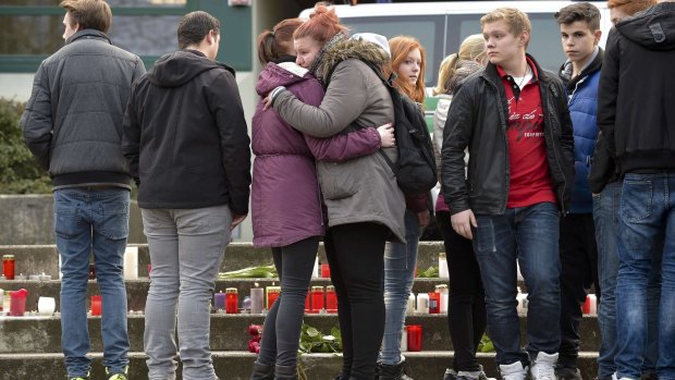 Students embrace in front of lit candles outside the Josef-Koenig-Gymnasium high school in Haltern am See.
