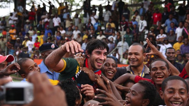 Hero: Johnathan Thurston is mobbed by fans after a Prime Minister's XIII match in Port Moresby.