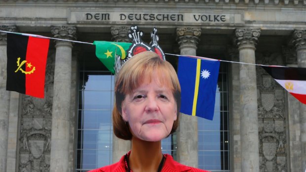 A woman wears an Angela Merkel mask during an anti-Nazi demonstration in front of the Reichstag building in Berlin.