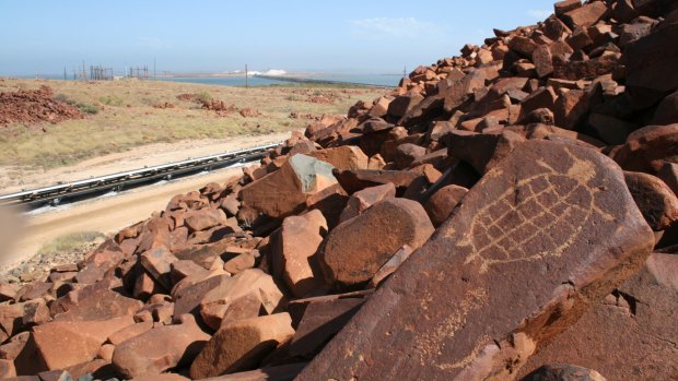 An engraving of a sea turtle on the Burrup Peninsula, Western Australia. The petroglyphs are near industrial complexes, including the Dampier salt stockpiles in the background. 