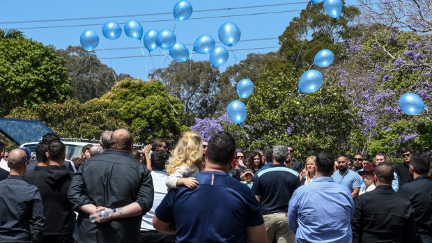 Blue balloons are released into the air by friends and family following the committal service for the boy. 