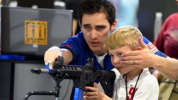 A boy is shown how to sight down an electronic rifle during the National Rifle Association's annual meeting in Nashville.